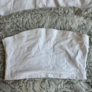Vit tubtopp från 157 - Säljer en enkel och stilren vit tubtopp från 157. Perfekt för varma sommardagar eller som ett basplagg i garderoben. Toppen är i mjukt material och har en bekväm passform.
