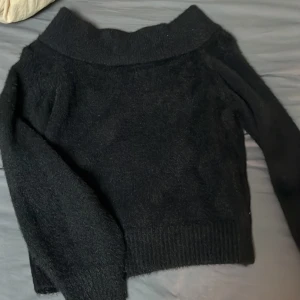 Svart stickadtröja från H&M - Säljer en mysig svart tröja från H&M. Tröjan har en bred krage och långa ärmar, perfekt för kyligare dagar. Den är tillverkad i ett mjukt material som ger en bekväm känsla. Passar bra till både jeans och kjol.