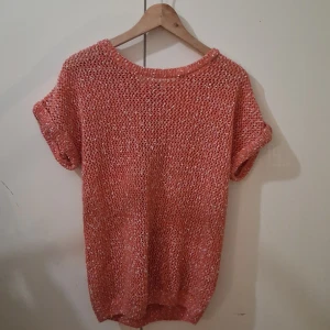 Korallfärgad stickad topp från Esmara - Säljer en snygg korallfärgad stickad topp från Esmara. Toppen har korta ärmar och en knytning i ryggen för en extra detalj. 