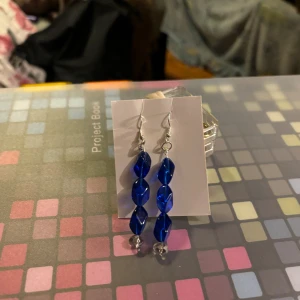 Blå glittriga örhängen - Snygga örhängen med blå glittriga pärlor i en elegant design. Perfekta för att ge en färgklick till din outfit.