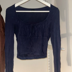 Mörkblå långärmad topp  - Snygg mörkblå topp med långa ärmar och knytning framtill. Perfekt för en stilren look. Passar bra till både jeans och kjol.