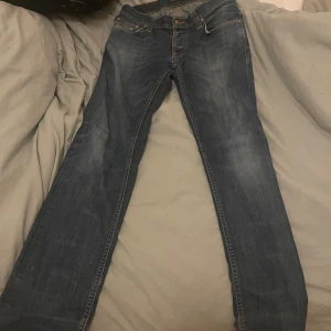 Blå jeansbyxor - Snygga blå nudie jeans och knappgylf. Perfekta för en avslappnad stil. De har en rak passform och är tillverkade i slitstarkt denim. Nu pris 1200 mitt pris 400 