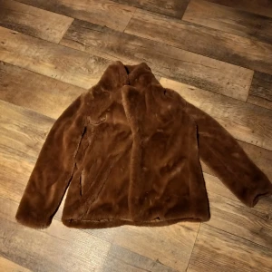 Brun pälsjacka från Reserved - Säljer en mysig brun pälsjacka (fakepäls) från Reserved. Jackan har en mjuk och fluffig yta med långa ärmar och en bekväm passform. Perfekt för kyliga dagar när du vill hålla dig varm och stilren.