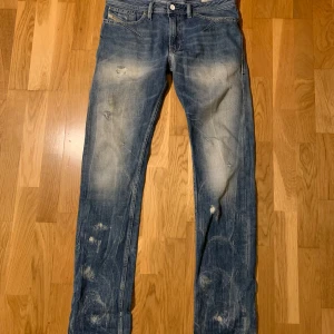 Diesel jeans - Snygga och unika blå jeans från Diesel i modellen Shioner. De har en slim passform med slitna detaljer och en klassisk femficksdesign. Perfekta för en avslappnad och unik stil. Skriv gärna ifall ni har mer frågor eller vill se mer bilder!