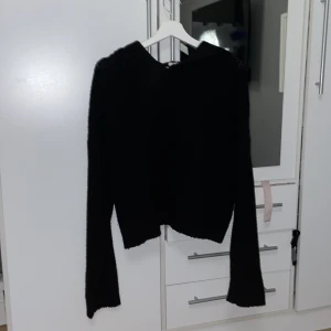 Svart stickad hoodie från NLY Trend - Säljer en svart stickad hoodie från NLY Trend. Den har långa ärmar och en mysig huva, perfekt för kyliga dagar. Tröjan är i storlek S och passar utmärkt för en avslappnad stil.