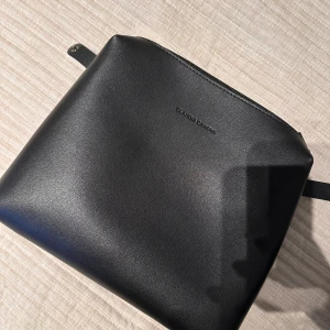 Svart väska från Claudia - Snygg och stilren svart väska/neccessär från Claudia  i skinn. Väskan har en praktisk dragkedja upptill och en minimalistisk design som passar perfekt för alla tillfällen.