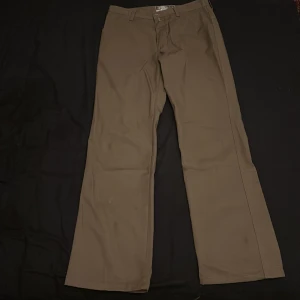 Bruna byxor från Psycho International - Snygga bruna byxor från Psycho International med en klassisk design. Tillverkade i en blandning av polyester och bomull, vilket ger en bekväm passform. Perfekta för en avslappnad stil.