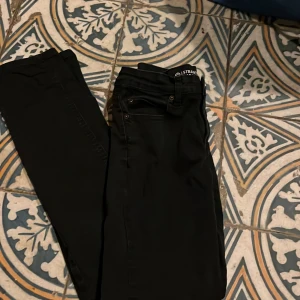 Svarta jeans från Cubus - Snygga svarta byxor från Stadium med en klassisk design. Perfekta för en stilren look. Byxorna har en rak passform och är tillverkade i ett bekvämt material.