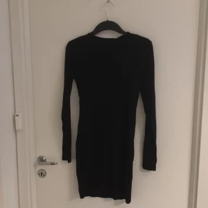 Svart långärmad klänning - Elegant svart långärmad klänning med en tight passform. Perfekt för en stilren look. Klänningen är enkel och klassisk, vilket gör den lätt att matcha med olika accessoarer.