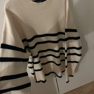 Randig tröja  - Säljer en snygg randig tröja i beige och svart. Tröjan har långa ärmar och en ribbad rund halsringning. Perfekt för en stilren look!
