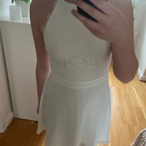 Vit spetsklänning från NLY Trend - Nu säljer jag min konfermations klänning från NLY Trend med spetsdetaljer och hög hals. Klänningen har en smickrande passform och är perfekt för speciella tillfällen. Den är ärmlös och har en dragkedja i ryggen för enkel påklädning. Den är använd en gång🤍