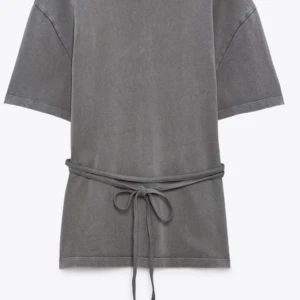Grå t-shirt med knytband - Säljer en grå t-shirt från Zara med knytband i midjan. T-shirten har korta ärmar och en avslappnad passform, perfekt för en casual look. Helt slutsåld