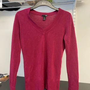 Vinröd tröja från H&M - Säljer en vinröd tröja från H&M med v-ringning och långa ärmar. Tröjan är i ett mjukt material och har ribbade kanter vid ärmslut och nederkant. Perfekt för kyligare dagar!