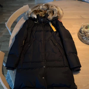 Blå vinterjacka från Parajumpers - Säljer en blå vinterjacka från Parajumpers med pälsfodrad huva och dragkedja. Jackan har en klassisk design med långa ärmar och flera praktiska fickor. Perfekt för kalla vinterdagar. Slim fit (long bear) heter modellen. Inga skador då den knappt är använd. Äkta päls. Qr kod i jackan. Helt ny kostar runt 11-10.000 kr! 