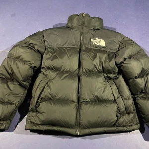 Svart dunjacka från The North Face - Säljer en svart dunjacka från The North Face i storlek S. Jackan har en dragkedja framtill och är långärmad med en pufferdesign som ger extra värme. Perfekt för kalla dagar.