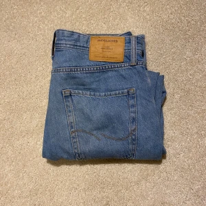 Blå jeans från Jack & Jones - Säljer ett par klassiska blå jeans från Jack & Jones i modellen Loose/Chris. De har en loose passform och är tillverkade i jeansmaterial med knappgylf och fem fickor. Priset kan alltid diskuteras
