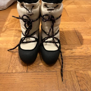 Bally Candye strl 38 - Vinterkängor från Bally helt fodrade med lamull. Så varma och snygga! Inköpta på NK Stockholm förra vintern för 5000 och bara provade en gång. Strl 38 Den vita delen på kängan är i mjukt skinn.