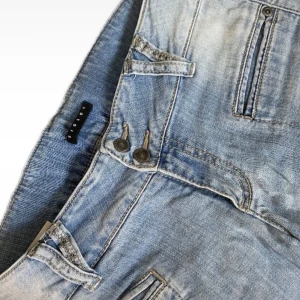 Ljusblå jeans med broderade bakfickor - Snygga ljusblå jeans med unika broderade detaljer på bakfickorna. Mid rise och straight leg men har en fin design och färg för den personen som har tiden att sy om dessa jeans om man vill ha en mer bootcut form! 