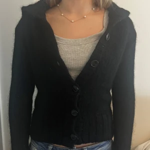 Svart kofta med knappar - Säljer en snygg svart kofta med stora knappar framtill. Den är perfekt för kyliga dagar och har en skön passform. Koftan är långärmad och har en ribbad kant vid ärmslut och nederkant. Passar både till vardags och lite finare tillfällen. Det är från HM och ganska tjock 