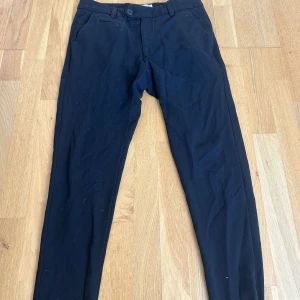 Svarta byxor från Les Deux - Säljer ett par stilrena svarta byxor från Les Deux i storlek 28. Byxorna har en klassisk design med knappar och är perfekta för både vardag och fest. De är i bra skick och har en snygg passform som passar de flesta tillfällen.