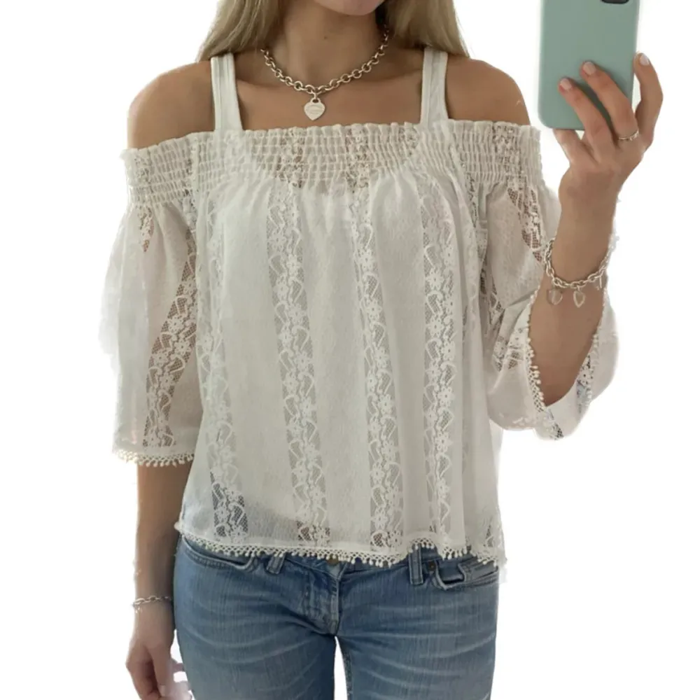 Säljer en superfin vit offshoulder blus med spetsdetaljer. Den har trekvartsärmar och en luftig passform, perfekt för sommardagar. Blusen har en elastisk överdel som ger en bekväm passform och söta spetskanter som ger en romantisk touch. Perfekt för både vardag och fest!. Yläosat.
