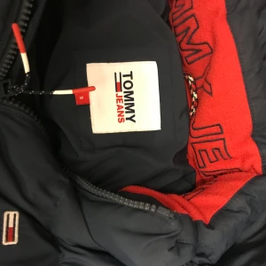Mörkblå dunjacka Tommy Hilfiger - Säljer en svart pufferjacka från Tommy Jeans i extremt bra skick. Perfekt för kalla vinterdagar. Den är vadderad och har en liten logga på bröstet och ärmen. Superbekväm och stilren! Storlek S nypris: 2600kr
