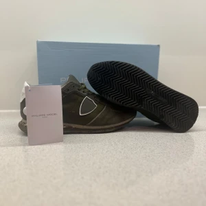 Gröna sneakers från Philippe Model - Säljer ett par snygga gröna sneakers från Philippe Model. De har en cool design med vita detaljer och en robust sula som ger bra grepp. Perfekta för både vardag och lite mer avslappnade tillfällen. Skorna är i mycket bra skick och kommer med originalförpackning.