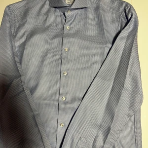 Blå mönstrad skjorta från Stenströms - dubbelmanschett  - Säljer en elegant blå slimlineskjorta från Stenströms i supermjuk bomull. Dubbelmanschett. Skjortan har ett diskret mönster och knappar framtill. Perfekt för både kontoret och mer formella tillfällen. Den är i mycket bra skick och redo för en ny ägare!