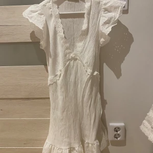 Vit sommarklänning - Säljer en superfin vit klänning från Trendyol i storlek 36. Den har vackra spetsdetaljer och volanger vid ärmarna och fållen. Perfekt för sommarens fester eller midsommarfirandet! 💫