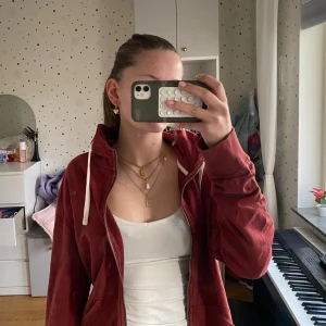 Säljer skit snygg vin röd hoodie!!! - Säljer en snygg röd hoodie med dragkedja och vita snören. Perfekt för en avslappnad stil och passar bra till både höst och vår. Den har en normal passform och är superbekväm att ha på sig. Perfekt för chill dagar eller när du bara vill ha något enkelt men stilrent. 🧡