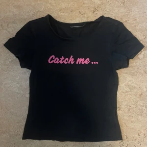 Svart t-shirt från Adidas - Snygg svart t-shirt från Adidas med texten 'Catch me ... if you can!' i rosa på både fram- och baksidan. Perfekt för en casual look eller träning. T-shirten har en normal passform och korta ärmar.