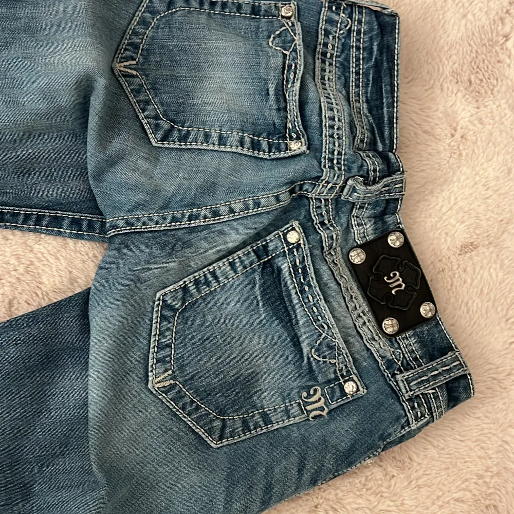 Säljer ett par snygga blå jeans från Miss Me i storlek 36. De har en bootcut-stil och är tillverkade i bomull med lite stretch för extra komfort. Jeansen har coola detaljer som broderade bakfickor och lågmidja säljer då dom inte kommer till användning dom är uppsydda i längden och passar mig som är 163cm lång🥰aldrig använda bara provade!. Jeans & Byxor.