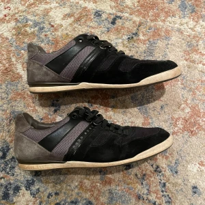Svarta sneakers med grå detaljer - Säljer ett par snygga svarta sneakers från Hugo Boss med grå detaljer, säljer pågrund av dem är för små.