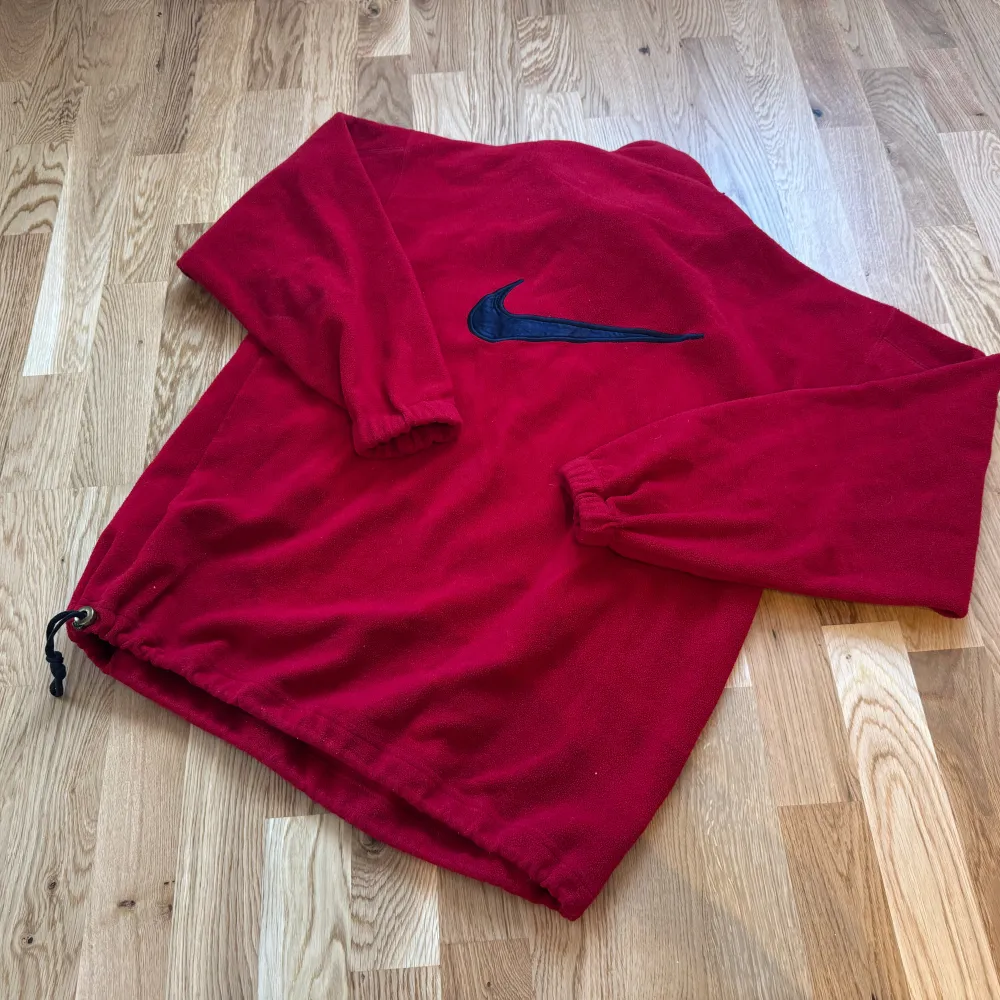 Säljer en röd fleece tröja från Nike i storlek XL men sitter som L. Den har en halv dragkedja och elastiska muddar vid ärmsluten. Perfekt för kyliga dagar med sin mjuka och varma känsla. Nike-loggan är broderad i svart på bröstet. Passar både för träning och vardag.. Tröjor & Koftor.