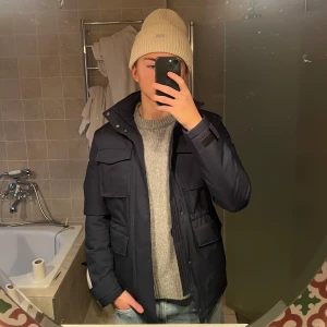 J Lindeberg field jacket  - Säljer en snygg mörkblå field jacket från J. Lindeberg i mycket bra skick, som ny! Den är fodrad och lite varmare samt vattenavvisande, perfekt till vintern/hösten! Nypris 4500kr mitt pris: 1299kr! Storlek S