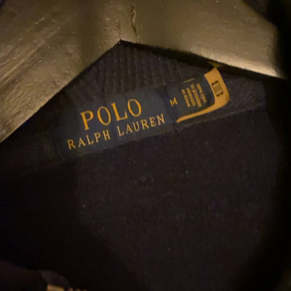 Säljer en snygg mörkblå hoodie från Ralph Lauren. Den har en dragkedja framtill och vita snören i huvan. Perfekt för en avslappnad stil och håller dig varm under kyliga dagar. Den klassiska loggan syns på bröstet. Passar perfekt till både jeans och joggers!. Tröjor & Koftor.