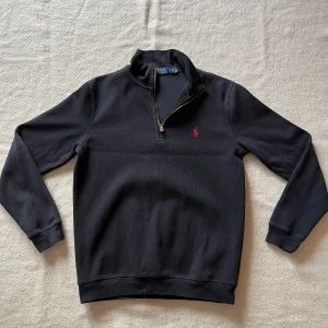 Svart half zip Polo Ralph Lauren - Säljer en stilren svart half zip från Polo Ralph Lauren i storlek M. Perfekt för både vardag och lite finare tillfällen. Superbekväm och lätt att matcha med det mesta! Säljer då den inte passar mig. Den är lite fläckig på vänster-innerarm, annars helt felfri! (Bild 2)