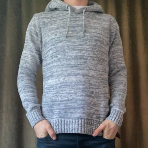 Grå stickad hoodie - Säljer en grå stickad hoodie i bra skick. Den har en liten fläck på magen (bild 3) men inget som egentligen stör! Därav priset🙌 Vid minsta fråga eller fundering hör av er🤝