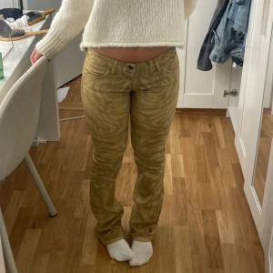 Beige mönstrade byxor - Säljer ett par snygga lågmidjade bootcut beige / senapsgul jeans med unikt mönster ifrån fornarina! 