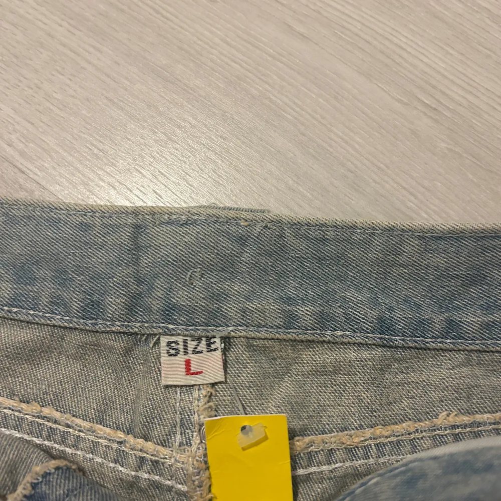 Snygg jeanskjol i storlek S, det står L men jag har storlek S och den passar mig. Coola strassdetaljer på fickorna och bältet. Kjolen har en sliten look med paljetter på de slitna delarna, vilket ger en trendig touch. Däremot så har dragkedjan gått sönder, men det går enkelt att fixa med ny dragkedja.🤗🤗. Kjolar.