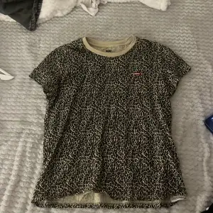 Säljer en cool leopardmönstrad t-shirt från Levi's. Den är kortärmad och har en liten röd Levi's-logga på bröstet. Perfekt för en avslappnad stil eller att piffa upp en outfit. Passar bra till jeans eller shorts!