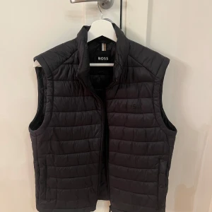 Svart Hugo Boss väst - Säljer en snygg svart quiltad väst från Boss i mycket bra skick. Perfekt nu till hösten och vintern. Priset är inte hugget i sten.