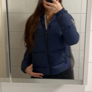 Mörkblå dunjacka/Eskimå jacket  - Säljer en mörkblå dunjacka med huva från D.BRAND. Jackan har en dragkedja framtill och praktiska fickor med dragkedjor. Perfekt för kalla vinterdagar. Hör av er vid funderingar eller fler bilder 🫶🏼