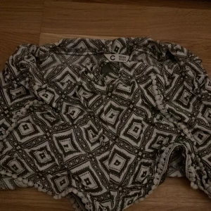 Mönstrade shorts i svart och vitt - Säljer ett par snygga shorts i svart och vitt med ett coolt geometriskt mönster. Perfekta för sommardagar eller en avslappnad fest. De är i bra skick och passar ungdomar i åldern 13-14 år. Superbekväma och lätta att matcha med en enkel t-shirt eller linne.