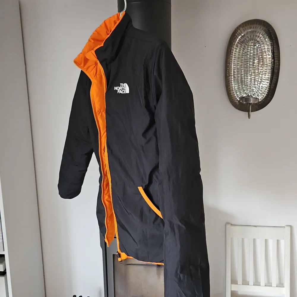 Säljer en supercool vändbar jacka från The North Face. Ena sidan är knallorange och den andra är svart med orange detaljer. Perfekt för höst och vår! Jackan har en dragkedja och är långärmad. Den är i mycket bra skick och redo för nya äventyr!. Jackor.