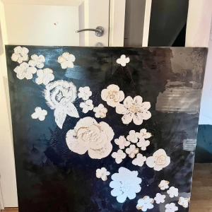 Svart tavla med vita blommor - Säljer en stor, fyrkantig tavla med en svart och grå bakgrund och vackra vita blommor. Blommorna är spaklade och har detaljer i guld och grått, vilket ger en elegant och modern känsla. Perfekt för att ge liv åt ett rum med en stilren och konstnärlig touch.✨Målat det själv✨kan ej skickas