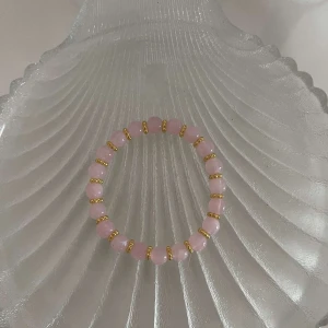 Rosa pärlarmband med gulddetaljer - Snyggt elastiskt armband med rosa pärlor och små guldfärgade detaljer. Perfekt för att ge en färgklick till din outfit. Passar både till vardags och festliga tillfällen. 💖