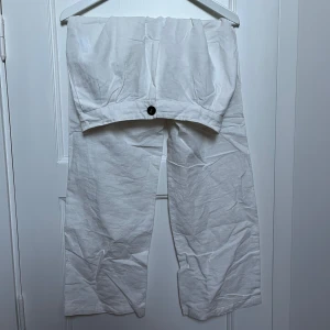 Vita linnebyxor med knapp - Säljer ett par vita linnebyxor i bra skick. De har en enkel design med en knapp framtill och är perfekta för sommaren. Byxorna har en loose passform och är tillverkade i ett lätt och luftigt material, vilket gör dem superbekväma att bära under varma dagar.