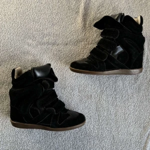isabel marant skor - Snygga svarta sneakers i mocka med kilklack och coola detaljer. Köpta här på plick, fick inte med något kvitto eller liknande så är inte säker på om dem är äkta. storlek 36:) kom gärna med frågor, priset är inte fast