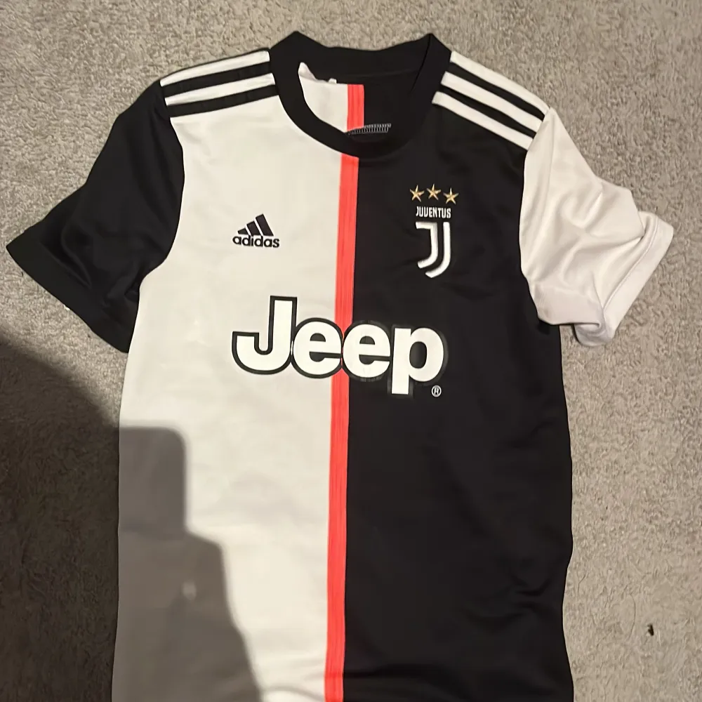 Säljer en Juventus fotbollströja med Dybala nummer 10. Tröjan är svart och vit med en röd rand i mitten. Den har korta ärmar och är i mycket bra skick. . T-shirts.